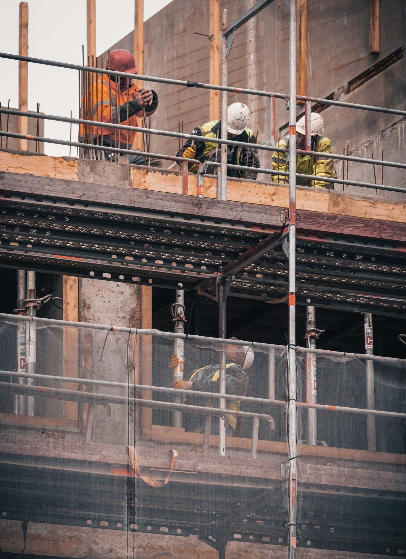 Scaffolding erected across the brick facade of a building with workers on the upper deck.